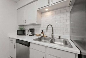 A modern kitchen with white cabinets, a stainless steel sink, a microwave, and a dishwasher. - Arlington 2BR • Walk to AT&T • Free Parking (Arlington)