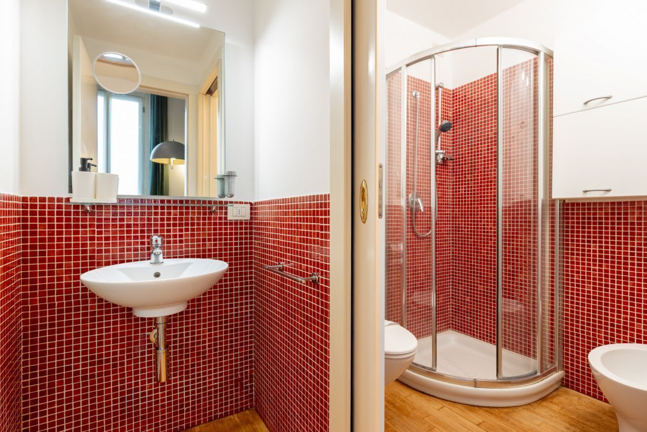 A bathroom with a white sink, a mirror, and a glass-enclosed shower.