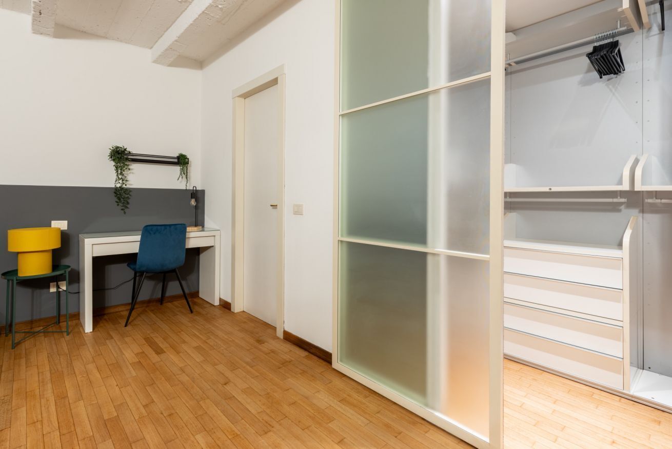 A room with a desk, chair, and a sliding closet door.