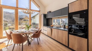Une cuisine moderne avec des meubles en bois, un micro-ondes noir et un coin repas comprenant une table et des chaises.