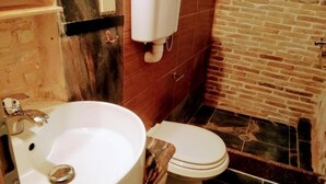 A bathroom with a white sink, a toilet, and a brick wall.