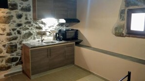 A compact kitchen with a stone wall, a microwave, and a sink.
