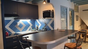 A modern kitchen with a central island, dark cabinets, and a microwave above the island. - SAUJON APARTMENT NEAR SPA (Saujon)