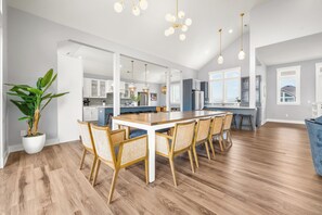 A spacious kitchen with a central island, wooden flooring, and pendant lighting. - Stargazer 10 bedroom Brand New Luxury Home on Hatteras Island (Hatteras)