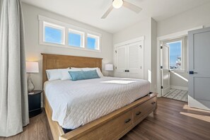 Ein Schlafzimmer mit einem großen Bett, einem Holz-Kopfteil, zwei Nachttischlampen, einem Deckenventilator und Blick auf die Stadt durch eine Tür.