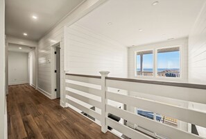 Ein Flur mit weißen Geländern und Blick auf das Meer durch ein Fenster.