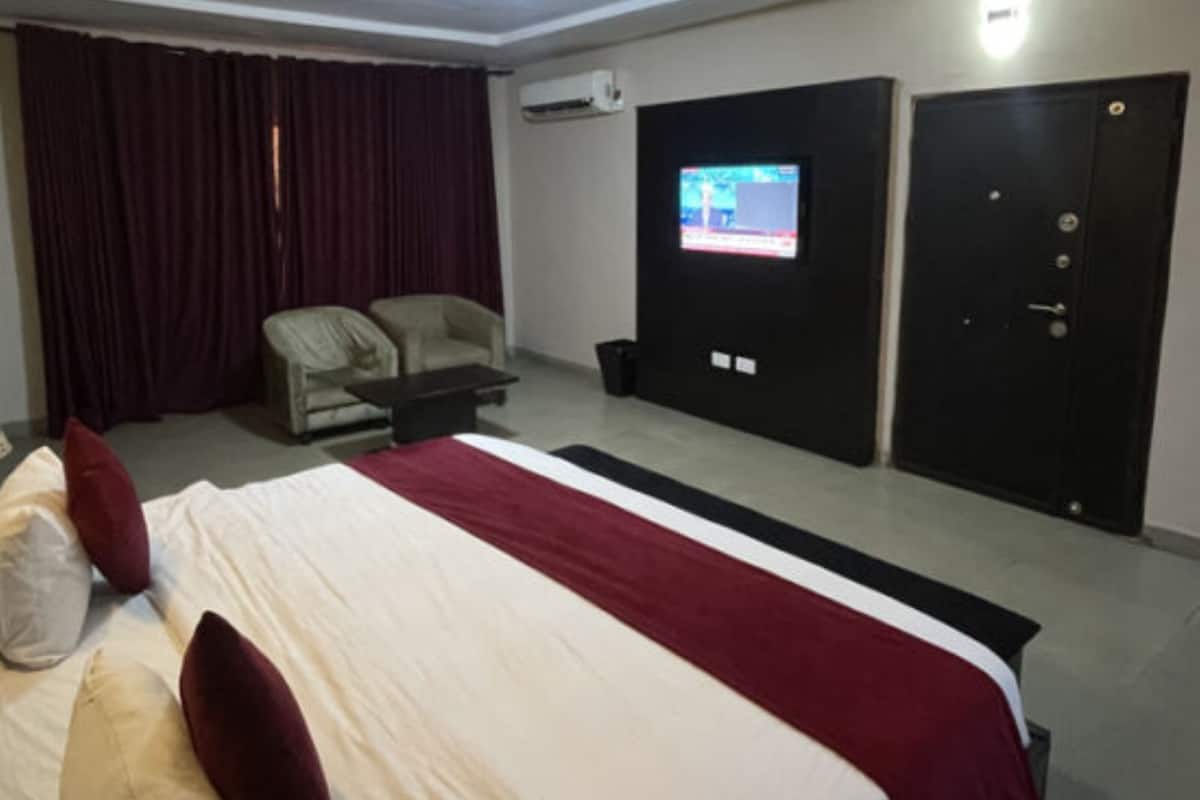 A hotel room with a large bed, a television, a desk, and a chair.