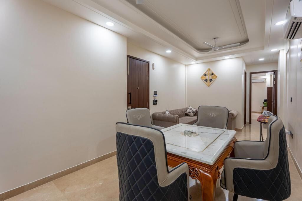 A dining area with a marble table and cushioned chairs, a sofa, and a decorative wall piece.