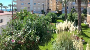 Un immeuble résidentiel doté de nombreux balcons, entouré d’une végétation luxuriante et de palmiers.