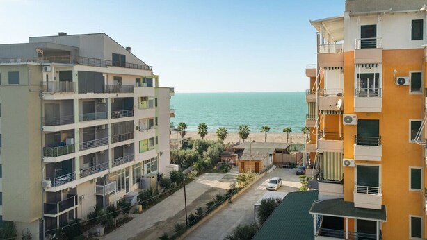 A coastal residential area with multi-story buildings, a beach, and a clear sky. - Sea View-Expansive Apartment by TOK (Golem)