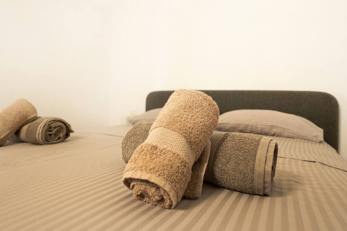 A bed with rolled towels and a pillow.