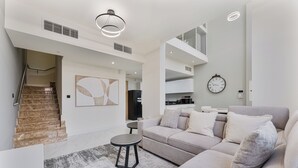 En moderne stue med sofa, sofabord og trappe.