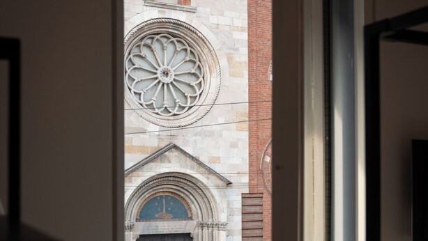 Une vue à travers une porte ouverte, donnant sur un bâtiment doté d’une grande fenêtre richement décorée et d ’une porte à cadre bleu.