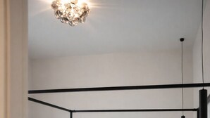 Une chambre à coucher avec un lit blanc, une tête de lit en métal noir et trois tableaux encadrés accrochés au mur.