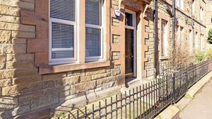 A stone building with a black metal fence, a door, and a window with shutters. - Refined 2-Bed Flat with Classic Edinburgh Charm (Edinburgh)