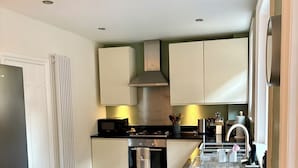 Une cuisine moderne avec des meubles blancs, un plan de travail noir et des appareils électroménagers en acier inoxydable.
