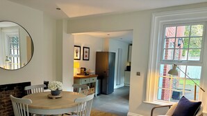 Un coin repas avec une table ronde, des chaises blanches et un miroir au mur.