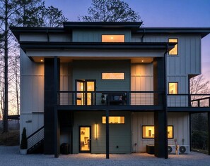 Ein modernes, zweistöckiges Haus mit Balkon, großen Fenstern und einer Garage.