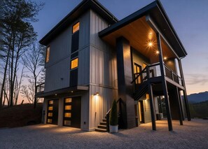 A modern two-story house with a balcony, large windows, and a driveway. - Mountain-modern 3BR cabin sleeps 8, hot tub, community boat dock and game room. (Bryson City)