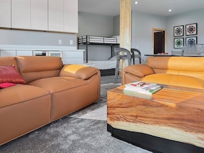 A modern living room with a sofa, a coffee table, and a bunk bed in the background. - Mountain-modern 3BR cabin sleeps 8, hot tub, community boat dock and game room. (Bryson City)