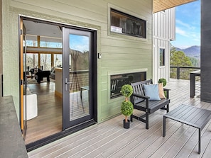 A modern outdoor deck with a bench, a small table, and a fireplace. - Mountain-modern 3BR cabin sleeps 8, hot tub, community boat dock and game room. (Bryson City)