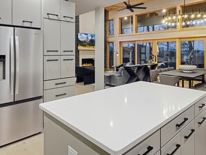 A modern kitchen with a large island, built-in appliances, and a dining area with a view. - Mountain-modern 3BR cabin sleeps 8, hot tub, community boat dock and game room. (Bryson City)
