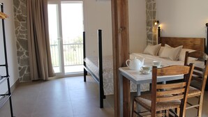 Een slaapkamer met een bed, een houten stoel, een tafel met theepot en kopjes, en een balkon met gordijnen.