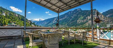 A terrace with wicker furniture and a view of mountains.