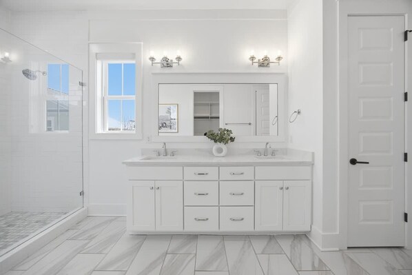 A modern bathroom with a large mirror, white cabinetry, and a shower area. - 7BR Heart of Home W Pool Near the Beach (Miramar Beach)