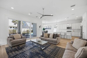 A modern living room with a sofa set, a coffee table, and a large window with a view of the outdoors. - 7BR Heart of Home W Pool Near the Beach (Miramar Beach)