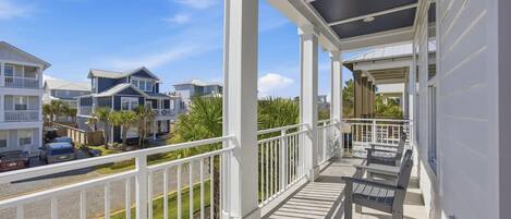 A covered balcony with a view of neighboring houses and a street.