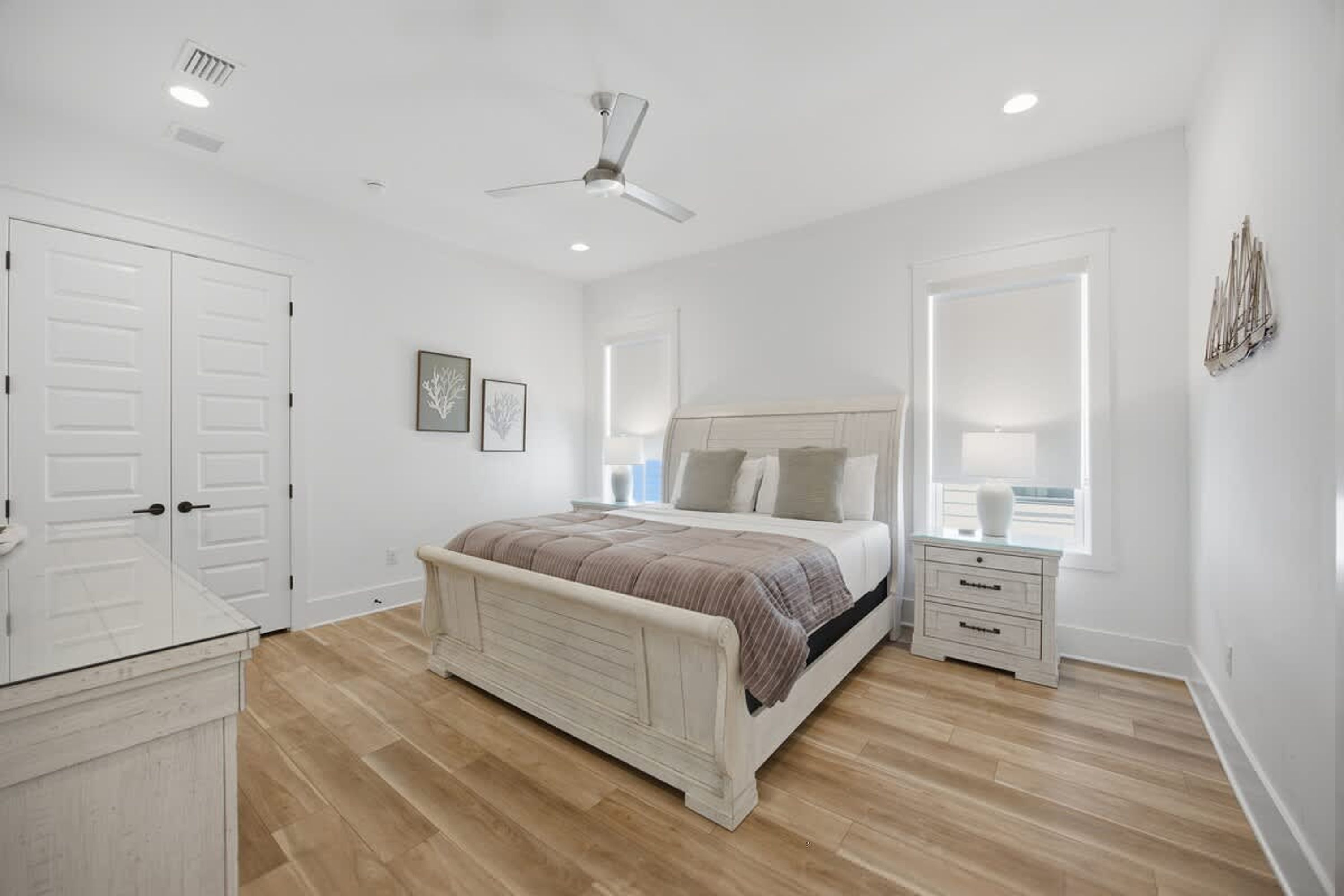 A bedroom with a bed, bedside tables, a wardrobe, and a ceiling fan.