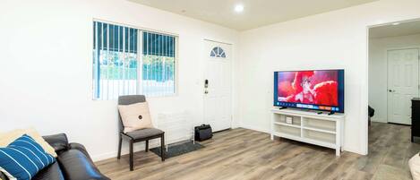 A living room with a leather sofa, a television, and a wooden floor.