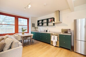 A modern kitchen with a wooden table, a built-in oven, and a microwave. - Above the Heath (London)