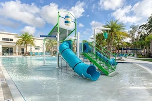 A water park with a blue slide and a water play area. - Luxurious 5-bedroom House With Pool Near Disney World - Perfect for Your Family 2613 (Kissimmee)