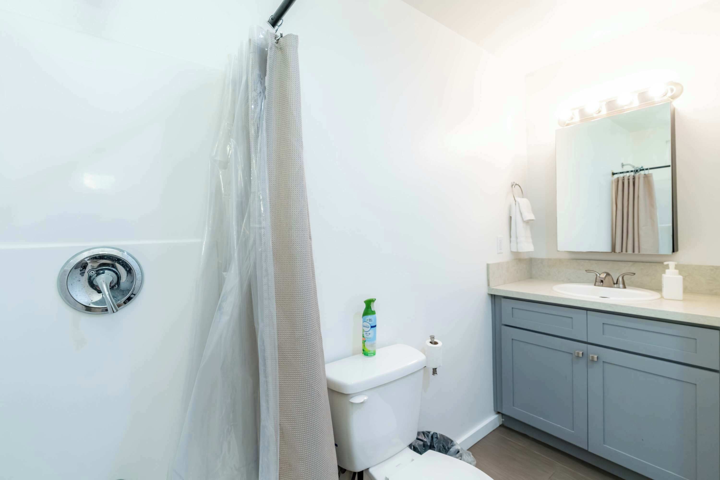 A bathroom with a shower curtain, toilet, sink, and mirror.