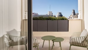Un balcon avec deux chaises et une petite table, une vue dégagée sur les bâtiments et un mur décoratif.