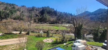 Paisagem montanhosa com céu claro, caminho pavimentado e um caminhão estacionado.