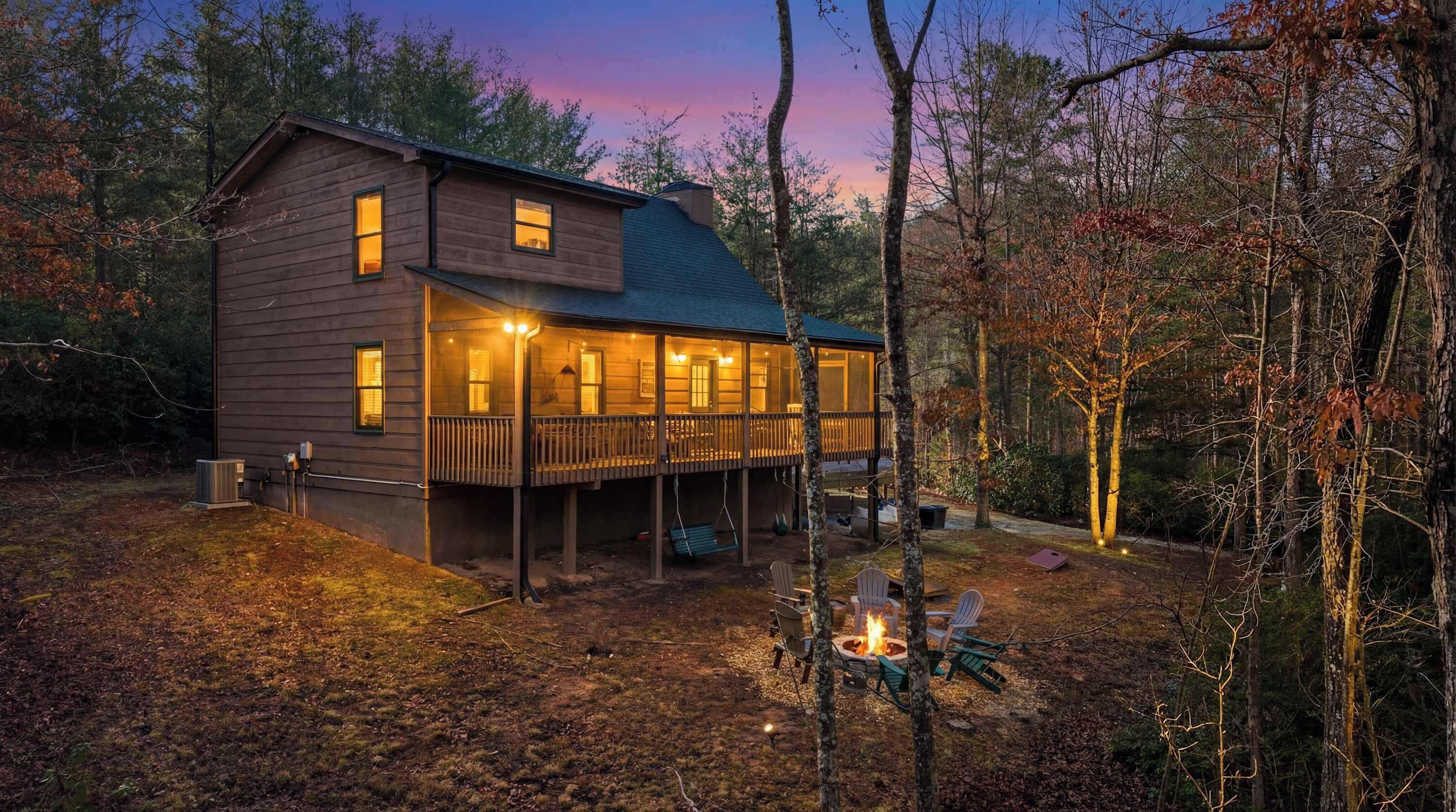 A wooden cabin with a deck, surrounded by trees.