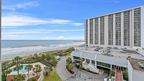 Ein Hochhotel mit Pool, Blick auf den Strand und einem Parkplatz.