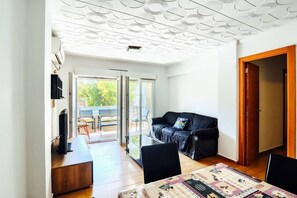 A modern living room with a sofa, a dining table, and a TV. - Spacious apartment on the beach for 6 people (València)