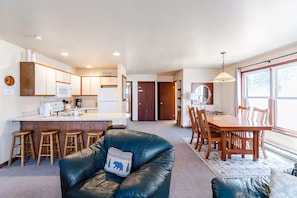 A modern kitchen with white cabinets, a microwave, and a dining area with wooden furniture.