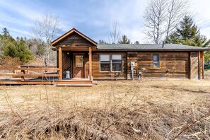 A rustic wooden cabin with a porch, a front door, and a window.