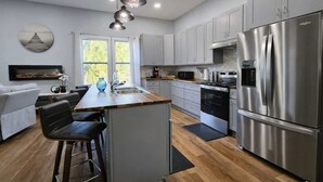 Uma cozinha moderna com eletrodomésticos de aço inoxidável, um espaço de jantar com banquetas altas e uma janela grande que oferece muita luz natural.