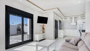 A modern living room with a sofa, a white coffee table, and a TV mounted on the wall.