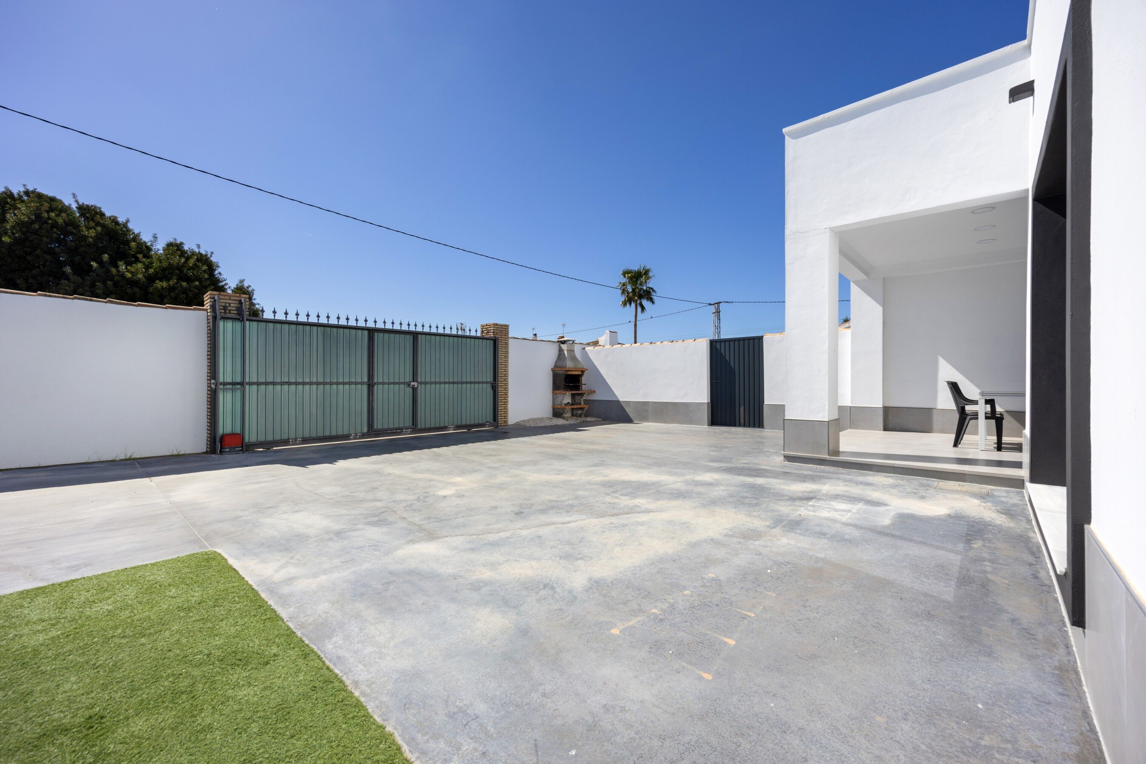 A modern building with a flat roof, a concrete patio, and a green lawn area.