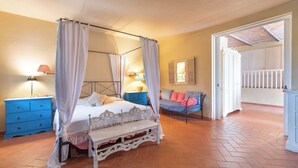 Une chambre à coucher avec un lit à baldaquin, une table de chevet, un banc et une vue sur un balcon extérieur.