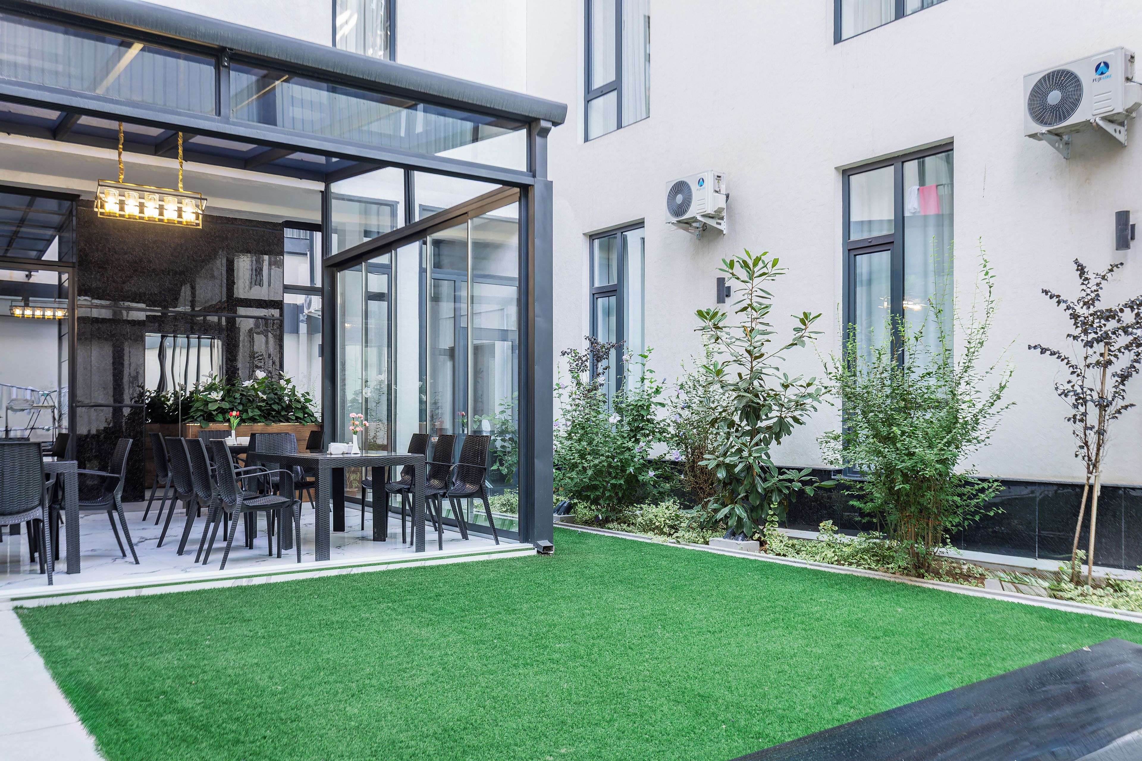 Un espace extérieur aménagé avec une structure vitrée, une table à manger et des chaises.