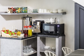 A compact kitchenette with a coffee machine, tea station, and glassware. - North Star Hotel (Tashkent)