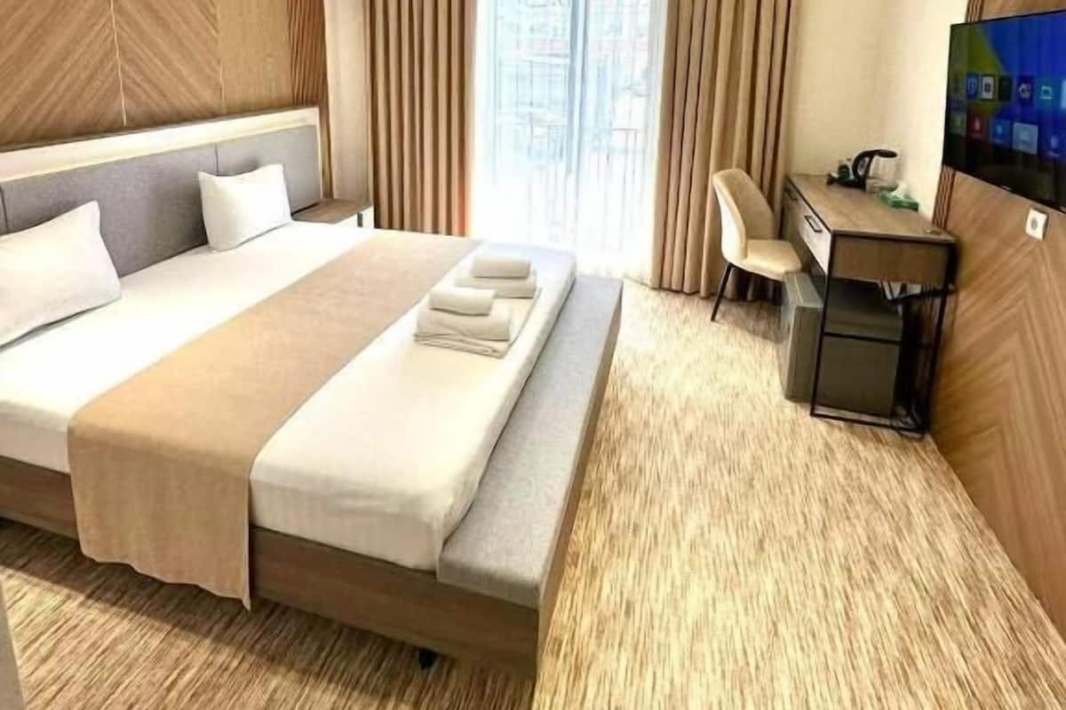 Una habitación de hotel con una cama grande, un escritorio y un televisor.